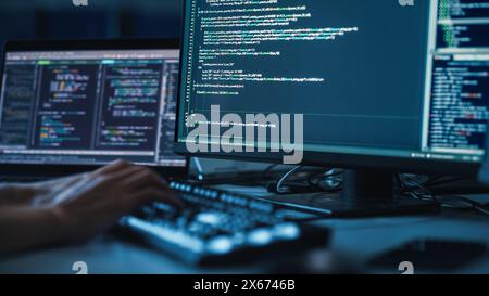 Close-up Focus on Person's Hands Typing on the Desktop Computer Illuminated Keyboard. Screens Show Coding Language User Interface. Software Engineer Create Innovative Commerce App. Program Development Stock Photo