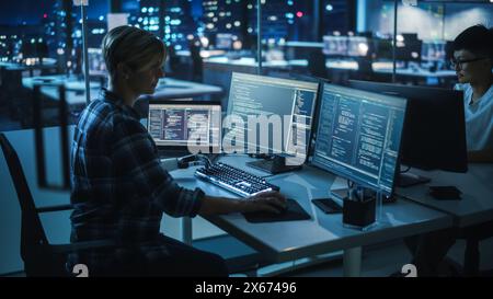 Night Office: Programmer With Disability Using Prosthetic Arm to Work on Computer Keyboard. Swift and Natural Use of Myoelectric Bionic Hand To Type Code for Software at Night. Stock Photo