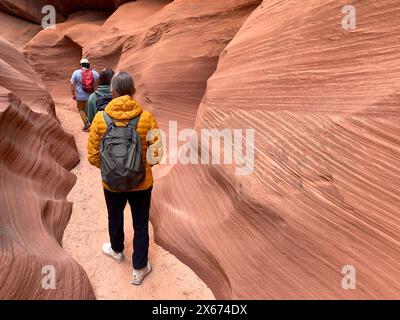 Tourists hike the entrance to Cardiac Slot Canyon in Page Arizona where beautiful striations and swirls begin to form in the wash where flash floods h Stock Photo