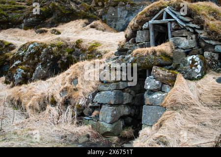 Turf house at foot of Drangurinn Rock in Southern Iceland. Eyjafjll mountains in southern Iceland near Ring Road, Route 1. Turfhouses linked to elves, Stock Photo