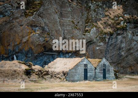 Turf house at foot of Drangurinn Rock in Southern Iceland. Eyjafjll mountains in southern Iceland near Ring Road, Route 1. Turfhouses linked to elves, Stock Photo