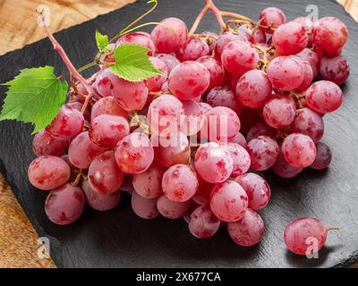 Cluster of red table grape with grape leaves isolated on white background. Stock Photo