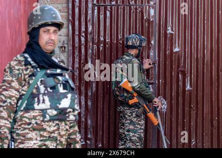 Srinagar, India. 13th May, 2024. Indian paramilitary troopers stand alert at a polling station during the fourth phase of the Lok Sabha, or lower house, of the Indian parliamentary elections in the outskirts of Srinagar. The 2024 Lok Sabha (lower house of Parliament) parliamentary elections mark the first major election in Jammu and Kashmir since New Delhi revoked Article 370, the region's special semi-autonomous status, in 2019. Credit: SOPA Images Limited/Alamy Live News Stock Photo