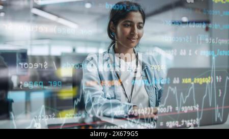 Diverse Office: Portrait of Beautiful Smiling Indian IT Programmer Working on Desktop Computer. Female Specialist Creating Innovative Software. Shot with Visual Effects of Running Code. Stock Photo