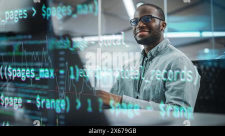 Real Office: Professional Black IT Programmer Working on Desktop Computer. Male Website Developer and Software Engineer Developing App, Video Game. Shot with Visual Effects of Running Code. Stock Photo