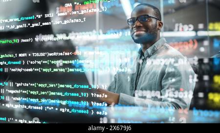 Real Office: Professional Black IT Programmer Working on Desktop Computer. Male Website Developer and Software Engineer Developing App, Video Game. Shot with Visual Effects of Running Code. Stock Photo