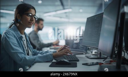 Diverse Office: Indian IT Programmer Working on Desktop Computer. Female Specialist Creating Innovative Software. Engineer Developing App, Program, Video Game. Writing Code in Terminal. Stock Photo