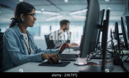 Real Diverse Office: Indian IT Programmer Working on Desktop Computer. Female Specialist Creating Innovative Software. Engineer Developing App, Program, Video Game. Writing Code in Terminal. Stock Photo