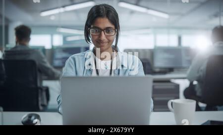 Diverse Office: Portrait of Smiling Indian IT Programmer Working on Desktop Computer. Female Specialist Create Innovative Software. Professional Engineer Develop App. Stock Photo