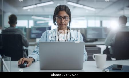 Diverse Office: Portrait of Smiling Indian IT Programmer Working on Desktop Computer. Female Specialist Create Innovative Software. Professional Engineer Develop App. Stock Photo