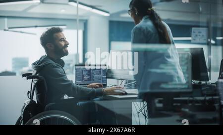 Disability-Friendly Office: Brilliant IT Programmer with Disability in a Wheelchair Talks with Colleague while Working on Computer. Software Engineers Develop Innovative App, Program. Stock Photo