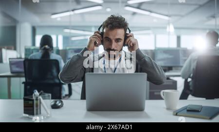 Office: Portrait of Smiling IT Programmer Put on Headphones, Work on Desktop Computer. Male Website Developer, Software Engineer Developing App, Video Game. Listening to Podcast, Music. Stock Photo