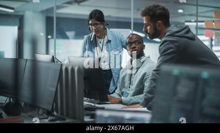 Diverse Multi-Ethnic Team in Modern Office: Teamwork of IT Programmers Gather Around Desktop Computer, Talking, Finding Solution. Specialists Create Software. Engineers Develop App, Program Stock Photo