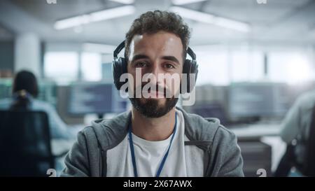 Office: Portrait of Happy IT Programmer Wearing Headphones Working on Desktop Computer. Male Software Engineer Developing App, Video Game. Listening to Podcast, Music Stock Photo