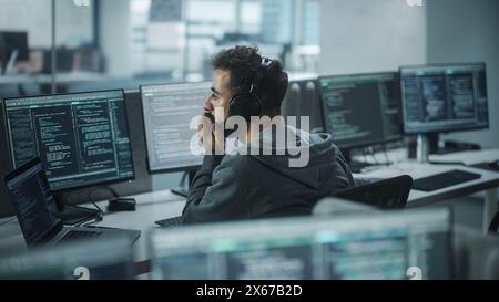 Office: Professional White IT Programmer Uses Headphones while Working on Desktop Computer. Male Website Developer, Software Engineer Developing App, Video Game. Listening to Podcast, Music. Stock Photo