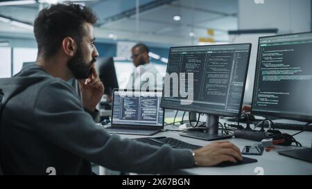 Diverse Office: Enthusiastic White IT Programmer Working on Desktop Computer. Male Specialist Creating Innovative Software. Engineer Developing App, Program, Video Game. Writing Code in Terminal Stock Photo