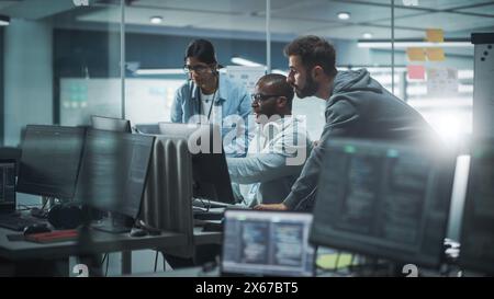 Diverse Group of Professionals Meeting in Modern Office: Brainstorming IT Programmers Use Computer Together, Talk Strategy, Discuss Planning. Software Engineers Develop Inspirational App Program Stock Photo