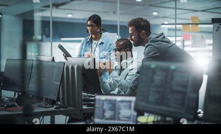 Diverse Group of Professionals Meeting in Modern Office: Brainstorming IT Programmers Use Computer Together, Talk Strategy, Discuss Planning. Software Engineers Develop Inspirational App Program Stock Photo