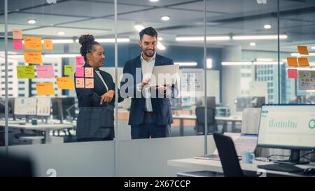 Young Businessman Talking with Experienced Colleague while Using Laptop Computer in Office. Employees Discuss Corporate, Financial and Marketing Projects. Specialists Work in Diverse Team. Stock Photo