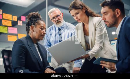 In Modern Office: Diverse Team of Managers Use Laptop and Tablet Computers at a Company Meeting Discussing Business Projects. Young, Motivated and Experienced Employees Brainstorm in Conference Room. Stock Photo