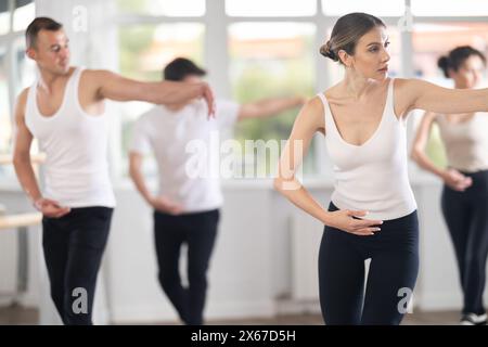 Experienced young female ballet dancer, dressed in white top and black leggings,  Stock Photo