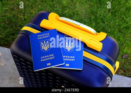 2 passports Ukraine citizens with inscription in Ukrainian - Passport of Ukraine lie on yellow blue suitcase in color of Ukrainian flag. Travel, refug Stock Photo