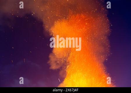 Sparks and smoke from a fire in the shape of a horse's head against a purple sky Stock Photo