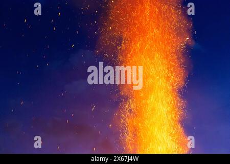 Column of smoke from a sparking fire with glittering sparks against a dark evening sky Stock Photo