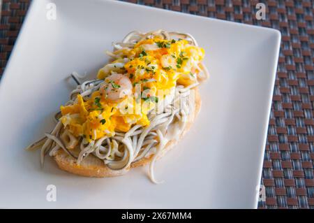 Spanish tapa: eels, prawns and egg with garlic and parsley on toast. Stock Photo