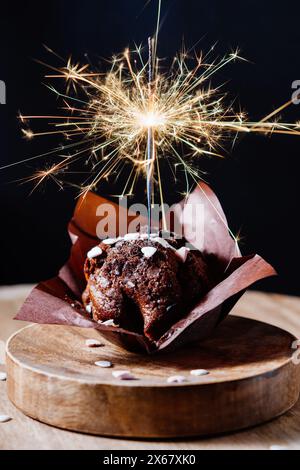 Festive chocolate muffin with sparkler on a dark background. Stock Photo