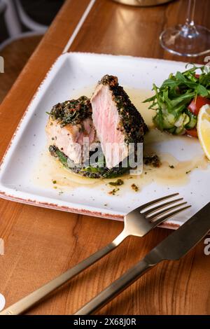 Tuna Steak with Spinach and Fresh Vegetables on a Table Stock Photo