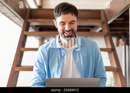 Smiling Young Man Working on Laptop, Sitting on Stairs Stock Photo