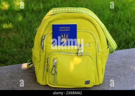 A passport of citizen of Ukraine with inscription in Ukrainian - Passport of Ukraine lies in green backpack. Travel concept, refugee, tourism, emigrat Stock Photo