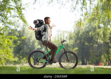 Backpacker riding a bicycle in a park Stock Photo