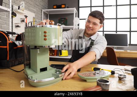 Male worker repairing coffee machine in workshop Stock Photo