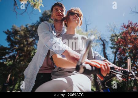 Young couple enjoying a sunny day biking in nature, embracing each other lovingly Stock Photo