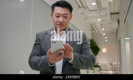 Asian adult 40s senior middle-aged businessman browsing smartphone app mobile chatting online business networking data connections chinese korean Stock Photo