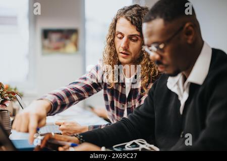 Two diverse colleagues brainstorming over a project in a bright office setting Stock Photo