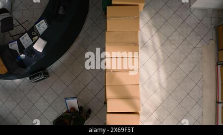 Top down view of warehouse chief supply chain officer examining cardboard box parcels in parallel, comparing findings. Depository staff members making sure stocks and inventory are well organized Stock Photo