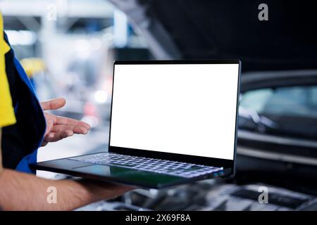 Trained repairman in garage using mockup laptop to follow checklist while doing maintenance on customer car. Precise specialist in repair shop does checkup on client vehicle helped by isolated screen device Stock Photo