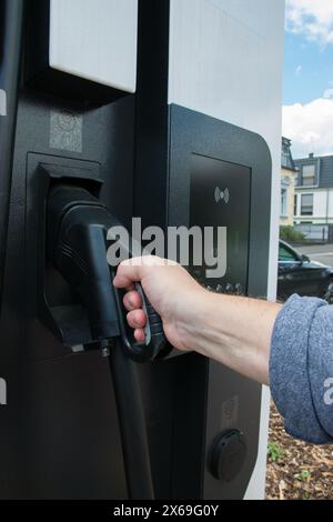 Hand holding gas pump in gas tank. Fuel, oil, gas filling - close up gas or electric station. Stock Photo