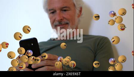 Image of emoticons floating over caucasian senior man using smartphone Stock Photo