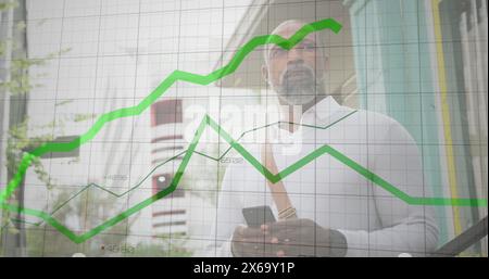 Image of financial data processing and green lines over african american man using smartphone Stock Photo