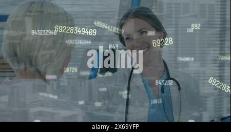 Image of numbers processing over caucasian female doctor with patient Stock Photo