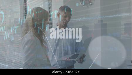 Image of graphs, loading circles, trading board, diverse coworkers discussing reports on laptop Stock Photo