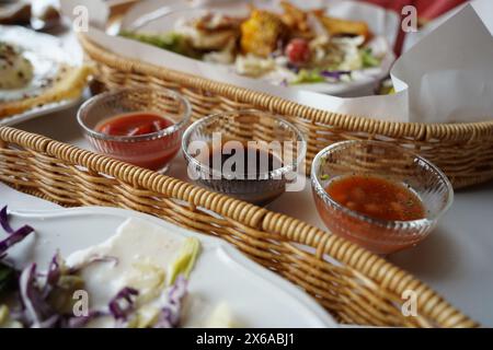 Restaurant food in a wicker basket with sauces on the table Stock Photo
