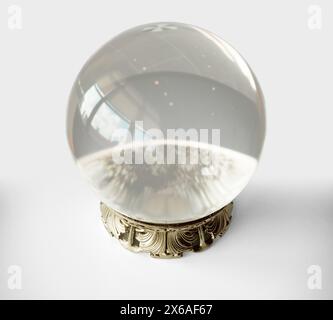 A fortune teller crystal ball with an ornate decorated brass base in an isolated white studio background - 3D render Stock Photo