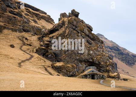 Turf house at foot of Drangurinn Rock in Southern Iceland. Eyjafjll mountains in southern Iceland near Ring Road, Route 1. Turfhouses linked to elves, Stock Photo