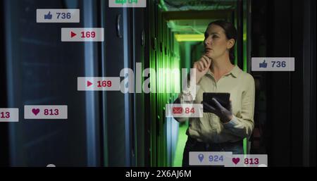 The caucasian female it technician is using a tablet to check the computer server Stock Photo