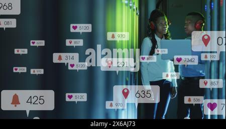 Image of social media icons on african american male and female engineers working at server room Stock Photo
